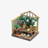 Miniature model of a greenhouse with plants and gardening tools on a white background