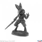 Gray miniature figurine of a character with a hood and spear on a white background