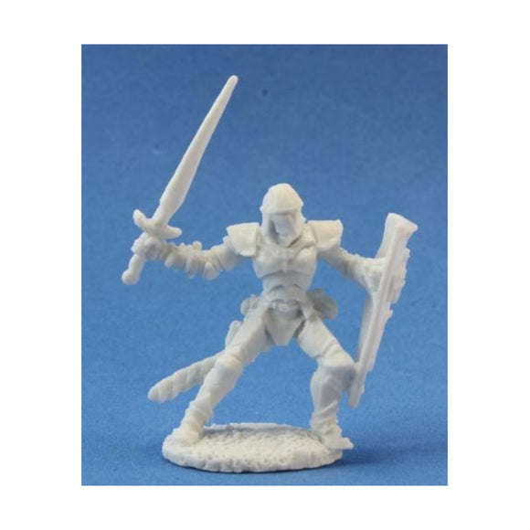 Unpainted miniature figure of a warrior with a sword and shield on a blue background