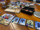 Board game setup on a wooden table with various cards and pieces.