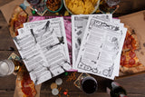 Game sheets on a table with pizza, drinks, and snacks