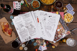 Board game components on a wooden table with snacks and drinks.