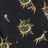 Patterned fabric with green snakes and yellow suns on a black background