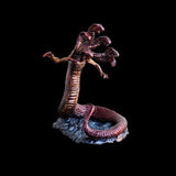 Statue of a creature with a snake-like body and humanoid upper body on a dark background