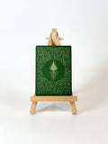 Green painting with a tree design on a wooden easel against a white background