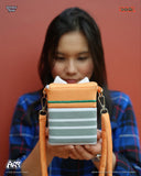 Person holding a striped pouch with orange straps against a red background