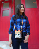 Person holding a cat-themed crossbody bag in front of a red door.