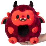 Red and black plush toy with horns and wings held by a hand on a white background