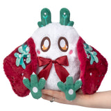 Plush toy with red bow and green antlers held by a hand on a white background