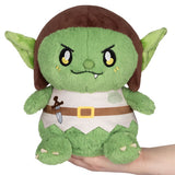 Green plush toy with brown hair and a belt, held in a hand on a white background
