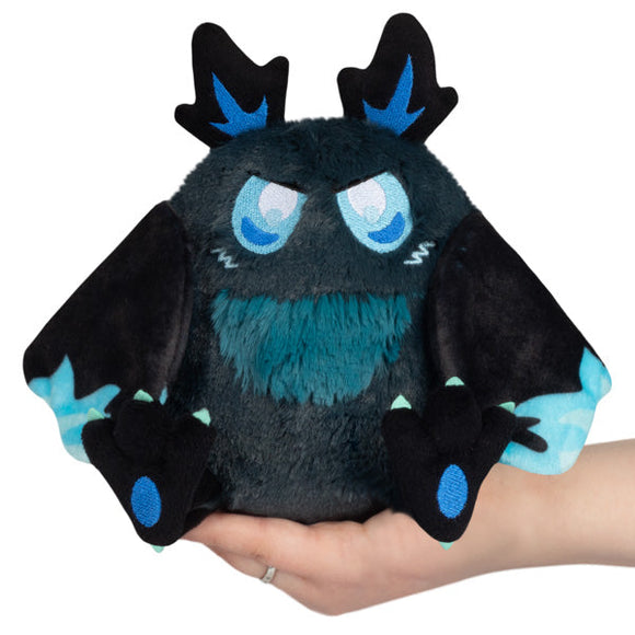 Plush toy with black and blue design held in a hand against a white background