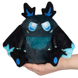 Plush toy with black and blue design held in a hand against a white background