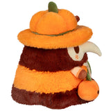 Plush toy resembling a bear wearing an orange pumpkin hat on a white background