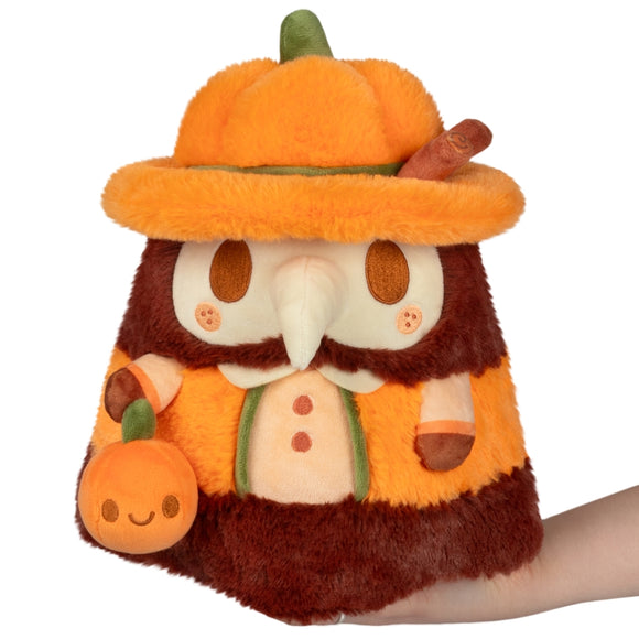 Plush toy resembling a bear with a pumpkin hat and pumpkin on a white background