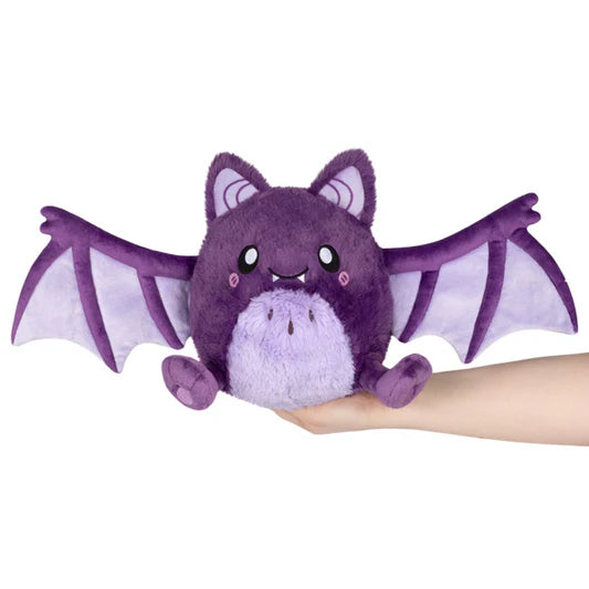 Purple plush bat toy held in a hand against a white background