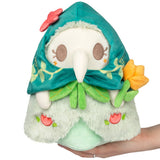 Plush toy with teal hood and floral design held by a hand on a white background