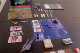 Board game setup with cards, pieces, and a map on a table