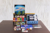 Board game components including cards, tokens, and a box labeled 'Vantage' on a wooden table.