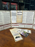 Game components including character sheets and rulebooks on a wooden surface with a bookshelf in the background.