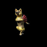 Gold dog figurine holding a red fan on a black background