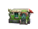 Miniature fantasy house with moss-covered walls and a red roof on a white background