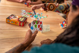 People playing a card game with colorful cards on a wooden table.