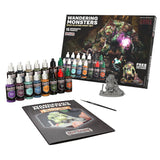 Wandering Monsters paint set with paint bottles, brush, and figurine on a white background