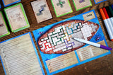 Board game with a ship design, cards, and markers on a wooden surface
