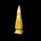 Gold obelisk with hieroglyphic designs on a black background
