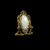 Gold-framed mirror with a white reflective surface on a black background