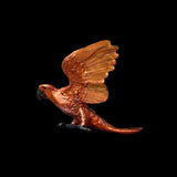 Bronze sculpture of a parrot in flight on a black background