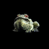 Metallic frog figurine on a black background