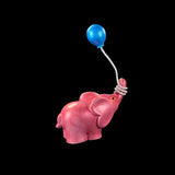 Pink elephant figurine with a blue balloon on a black background