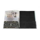 Open notebook with black pages and patterned cover on a white background