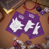 Two purple cards with a cartoon character on a brown surface with dice and other items.