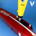 Yellow drill being used on a red model airplane with 'N710AP' on a blue background