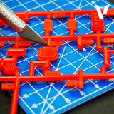 Red plastic model parts on a blue cutting mat with a knife
