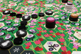 Close-up of a board game with colorful tiles and pieces on a floral-patterned board.