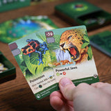 Card featuring a leopard and poison dart frog with game pieces on a wooden table.