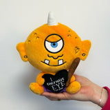 Plush toy cyclops held in a hand against a white background