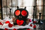mothman plush holding heart with text on a table