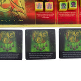Close-up of game cards with decorative designs and text, featuring a colorful box in the background.