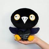 raven plush holding a black heart with text