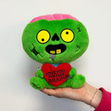 Green plush zombie toy with a heart saying 'I love you for your brains' on a white background
