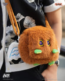 Brown plush bag with cartoon face held by a person wearing a black floral dress.