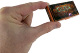A hand holding a small decorative box labeled 'QUIA' against a plain white background.