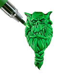 Paint marker being applied to a mini monster head on a white background