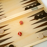 Wooden backgammon board with two red dice and pieces on a light surface