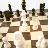 Close-up of a chessboard with pieces, focusing on white pawns and black rooks.