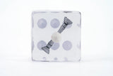 Clear cube with gray bow and purple circles on a white background